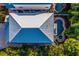 Aerial view of a modern home with a large roof next to a pool and surrounded by lush greenery at 318 64Th St, Holmes Beach, FL 34217
