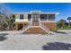Beautiful elevated home with a double staircase, light yellow siding and covered area underneath at 32 Palm Dr, Placida, FL 33946