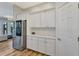 Bright pantry with ample white cabinetry, stainless steel fridge, and decorative backsplash on hardwood floors at 32 Palm Dr, Placida, FL 33946