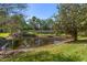 A view of a pond with reflective waters lined with lush green grass and mature trees, in a serene backyard setting at 3671 Parkridge Cir # 8-201, Sarasota, FL 34243