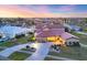 Beautiful exterior of a home with a circular driveway, lush lawn, and manicured landscaping during the evening at 4405 Harbor Blvd, Port Charlotte, FL 33952