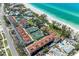 Scenic aerial view of beachside condos with a tennis court, pool, and lush greenery at 5055 Gulf Of Mexico Dr # 232, Longboat Key, FL 34228