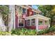 A red home with traditional architecture and a sunroom is surrounded by lush green vegetation at 624 19Th W St, Bradenton, FL 34205