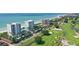 Expansive aerial view showcasing beachfront condos alongside a lush green golf course and ocean at 675 Longboat Club Rd # 23A, Longboat Key, FL 34228