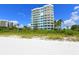 Condominium exterior view from beach shows white building with blue balconies and lush landscaping at 675 Longboat Club Rd # 23A, Longboat Key, FL 34228
