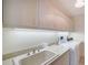 Bright laundry room features built in cabinets, utility sink, and modern washer and dryer at 675 Longboat Club Rd # 23A, Longboat Key, FL 34228