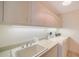 Bright laundry room features built in cabinets, utility sink, and modern washer and dryer at 675 Longboat Club Rd # 23A, Longboat Key, FL 34228