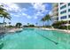 Large outdoor swimming pool surrounded by lounge chairs, umbrellas, and palm trees with the building exterior in the background at 675 Longboat Club Rd # 23A, Longboat Key, FL 34228