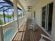 Long balcony with wooden floors, rocking chairs, and views of a lake and screened-in pool at 7538 Camden Harbour Dr, Bradenton, FL 34212