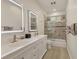 Bathroom with double vanity, framed mirrors with LED lights, and a bathtub with glass enclosure at 7538 Camden Harbour Dr, Bradenton, FL 34212
