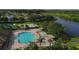 Aerial view of a community pool with lounge chairs, shade structures, and a splash pad surrounded by lush landscaping at 7538 Camden Harbour Dr, Bradenton, FL 34212