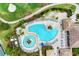 Aerial view of a community pool with a unique shape, many chairs, umbrellas, and lush landscaping at 8304 Grand Estuary Trl # 104, Bradenton, FL 34212