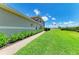 Townhome exterior featuring a brick walkway, lush lawn, and serene pond views, creating a tranquil outdoor living space at 8304 Grand Estuary Trl # 104, Bradenton, FL 34212