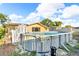 Backyard featuring an above-ground pool with ladder, deck, and mature trees under a blue sky at 9430 Glen Moor Ln, Port Richey, FL 34668