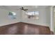 Spacious bedroom featuring wood floors, white walls, ceiling fan, and large windows with backyard view at 9430 Glen Moor Ln, Port Richey, FL 34668