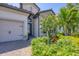 Close up exterior view of a single Gathering home with a brick driveway, three-car garage, and tropical landscaping at 7036 Highgate Ln, Lakewood Ranch, FL 34202