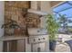 Outdoor kitchen featuring a stainless steel built in gas grill, stone accents and overhead vent at 7036 Highgate Ln, Lakewood Ranch, FL 34202