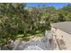 Aerial backyard view with brick patio, lush greenery and stone staircase and balcony at 1577 Alexander Rd, Belleair, FL 33756