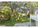 Landscaped backyard with mature trees, stone patio, and white railing at 1577 Alexander Rd, Belleair, FL 33756