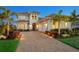 A beautifully landscaped two-story home featuring a brick driveway, three-car garage, and lush tropical landscaping at 17114 Verona Pl, Lakewood Ranch, FL 34202