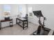 Bright office with two windows, dark wood desk, and exercise bike with monitor at 17114 Verona Pl, Lakewood Ranch, FL 34202