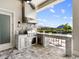 Outdoor kitchen area with stainless steel grill, stone accents, and bar seating overlooking the backyard at 17114 Verona Pl, Lakewood Ranch, FL 34202