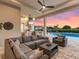 Expansive outdoor living space with outdoor kitchen, comfortable seating, and a beautiful pool at sunset at 17114 Verona Pl, Lakewood Ranch, FL 34202