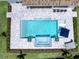 Aerial view of a modern pool and spa surrounded by a gray tile deck, landscaping and outdoor seating at 17114 Verona Pl, Lakewood Ranch, FL 34202