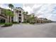 Exterior shot of the condo building showing a covered parking area, mature palm trees, and landscaping at 17118 Vardon Ter # 307, Bradenton, FL 34211