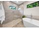 Modern bathroom with sleek glass-enclosed shower, free-standing tub, and natural light from a window at 2124 Wisteria St, Sarasota, FL 34239