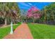 Scenic park pathway lined with lush grass and tall palm trees, featuring a vibrant pink blossom tree on a sunny day at 2124 Wisteria St, Sarasota, FL 34239