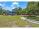 A vibrant playground with colorful equipment sits on a lush green lawn, shaded by mature trees and accessible via a paved path at 2124 Wisteria St, Sarasota, FL 34239