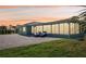 Rear exterior of home at dusk with large brick patio, lounge chairs, and ample green space at 217 Giotto Dr, Nokomis, FL 34275