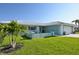 Charming teal home boasts lush green lawn, mature palm trees, and tiled roof at 217 Giotto Dr, Nokomis, FL 34275
