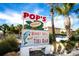 POP'S Waterfront restaurant sign in front of lush tropical vegetation, palm trees, blue skies and light clouds at 217 Giotto Dr, Nokomis, FL 34275