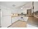 Well-lit kitchen featuring white appliances, white cabinets, granite countertops, and neutral backsplash at 219 Marlin Dr, Punta Gorda, FL 33950