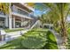 Landscaped backyard with a putting green, patio, and a modern home with an exterior staircase at 224 Chilson Ave, Anna Maria, FL 34216