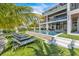 Backyard with a pool, lounge chairs, green lawn, and a modern home featuring a three-story design at 224 Chilson Ave, Anna Maria, FL 34216