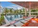 Inviting outdoor pool area with a covered patio, lounge chairs, and lush palm trees at 224 Chilson Ave, Anna Maria, FL 34216