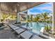 Covered outdoor living space with a beautiful pool, stepping stones, and a view of tropical landscaping at 224 Chilson Ave, Anna Maria, FL 34216