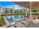 Inviting outdoor pool area with a covered patio, lounge chairs, and lush palm trees at 224 Chilson Ave, Anna Maria, FL 34216