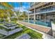 Gorgeous backyard featuring a large in-ground pool with sun loungers, lush grass, and multi-story home in the background at 224 Chilson Ave, Anna Maria, FL 34216