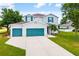 Two-story home featuring a lush lawn, a two car garage, and gray facade with turquoise shutters at 25364 Tether Ln, Punta Gorda, FL 33983