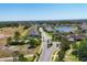 Aerial view of a Sun City Center neighborhood with a community pool, gate, golf course, and pond at 302 Crystal Downs Ct, Sun City Center, FL 33573