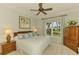 Bright bedroom featuring large window with serene views, complemented by elegant furnishings and a ceiling fan at 410 Wellington, Venice, FL 34292