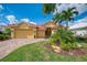 Beautiful home with red tile roof, lush landscaping, brick paver driveway, and a two-car garage at 410 Wellington, Venice, FL 34292
