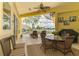 Enclosed patio features a ceiling fan, dining set, and seating with a view of the pool and lake at 410 Wellington, Venice, FL 34292