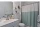Bright bathroom featuring a single vanity, shelving, a toilet, and a shower with a blue shower curtain at 4318 Deep Creek Ter, Parrish, FL 34219