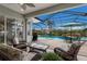 Back patio with chairs overlooks screened-in pool area, waterfall, grill, and shade umbrella at 4355 Pompano Ln, Palmetto, FL 34221