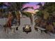 Backyard fire pit with seating area surrounded by tropical landscaping at dusk at 4440 Yacht Club Dr, Venice, FL 34293
